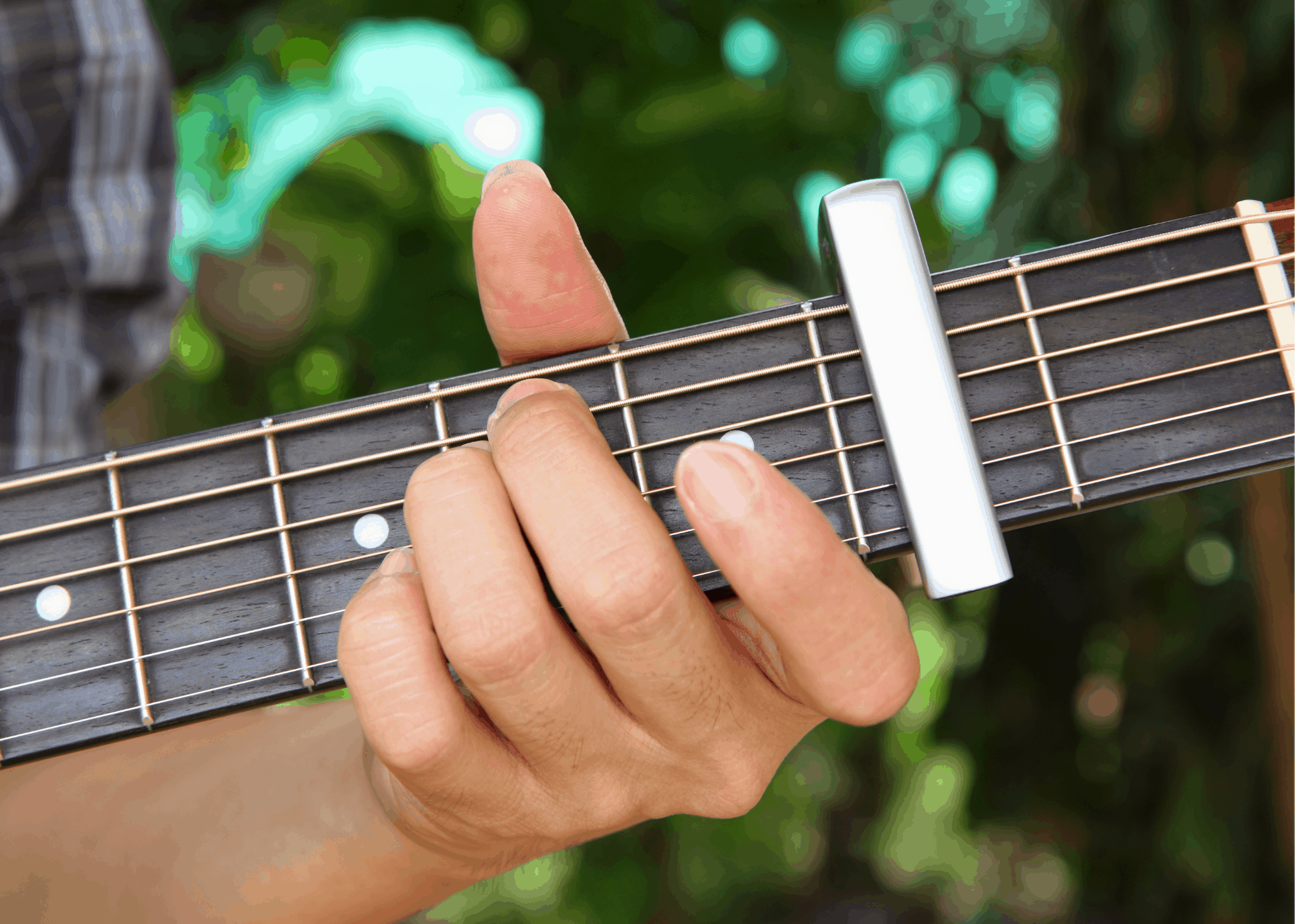 person playing a guitar using a capo